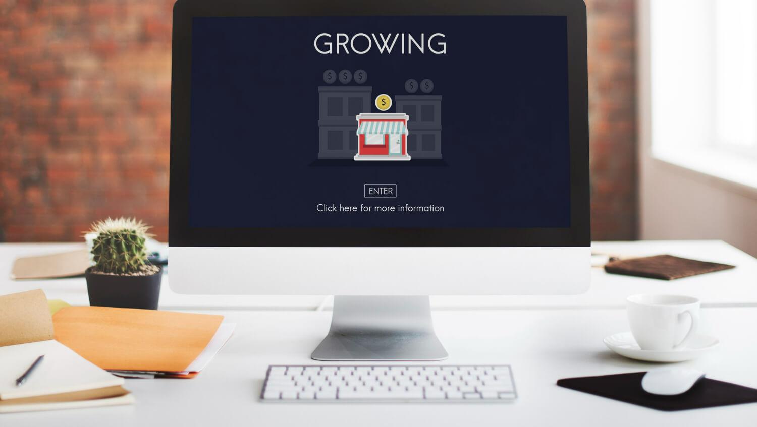 Groei visualiseren: desktopmonitor op bureau met 'groeiende' tekst op scherm