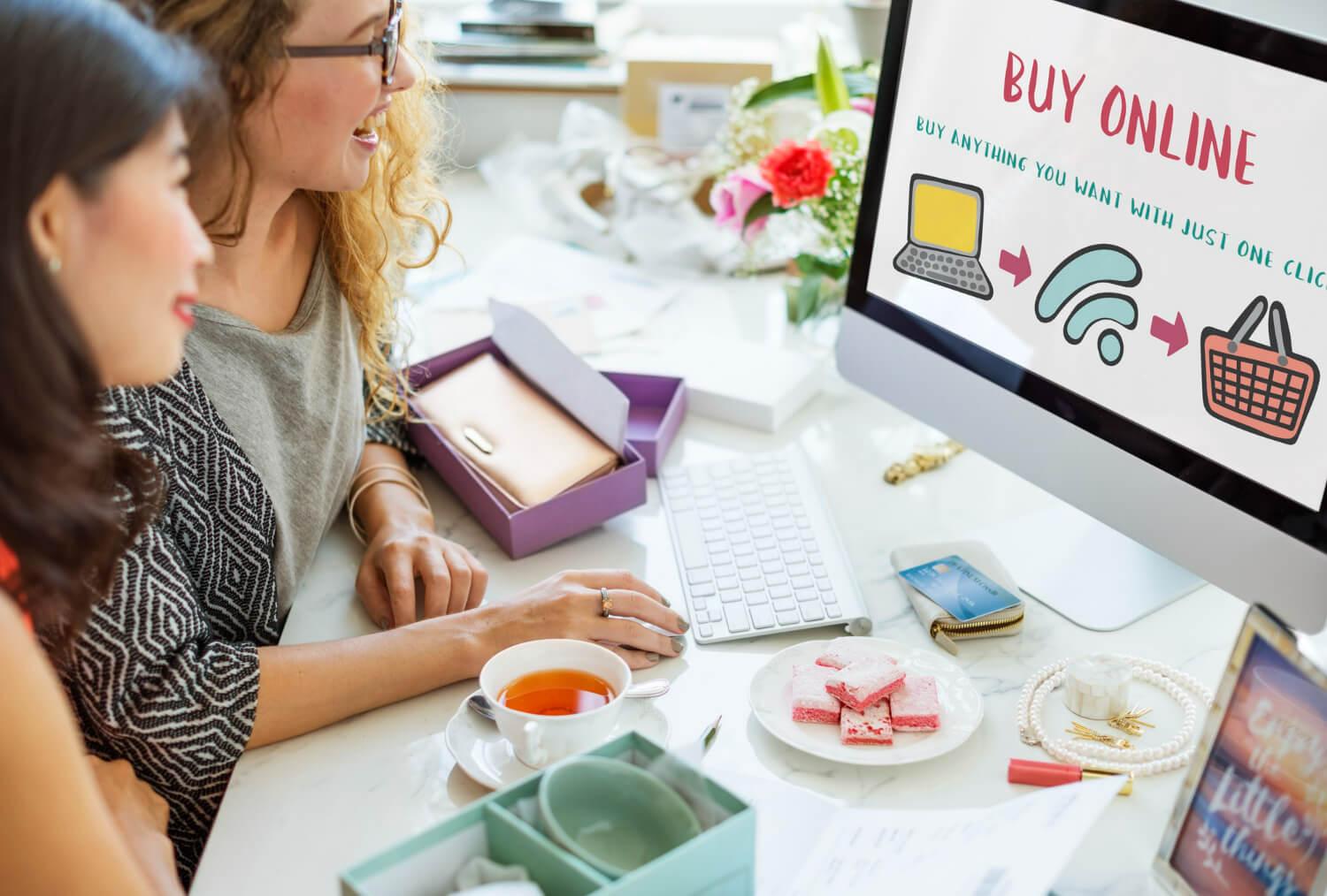Twee dames zitten voor een computerscherm met de tekst 'Buy Online" met het ultieme stappenplan voor een webshop